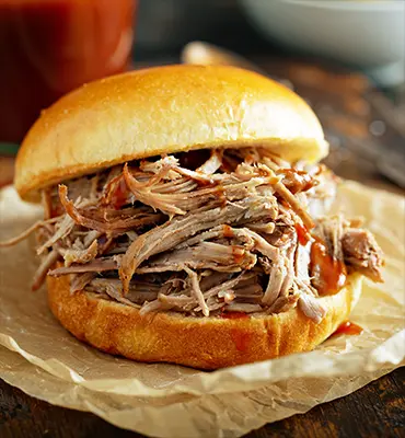 Enjoy a delectable pulled pork sandwich, deliciously served on genuine parchment.