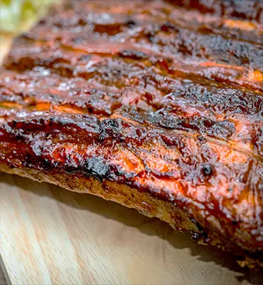 Succulent BBQ ribs served on a rustic wooden cutting board.