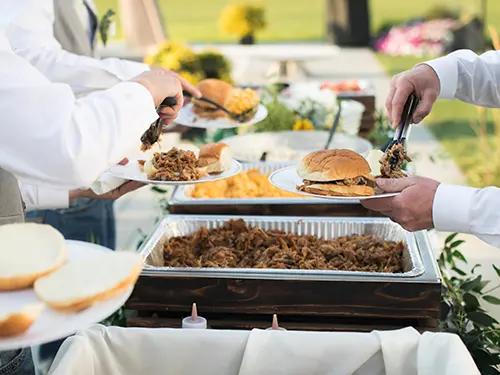 A team of men catering at an outdoor buffet event.